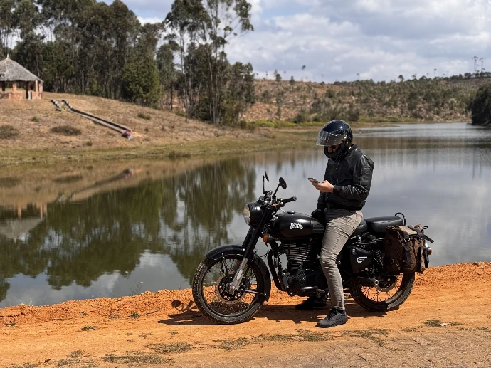Romain en moto à Madagascar en train de répondre à un client